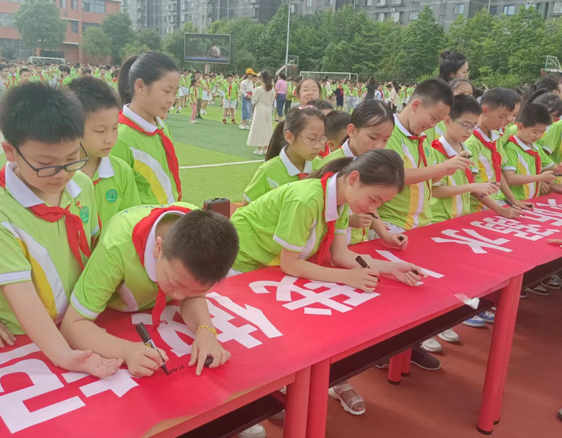 同学们纷纷在防溺水宣传横幅上签名。