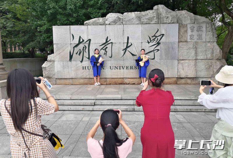  “湖南大学”校碑前，即将毕业的学生在轮流走位拍摄毕业纪念照。
