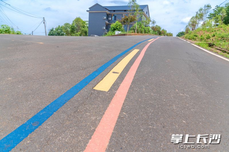 画着五彩标志线的彩虹路在乡村美丽屋场中蜿蜒穿行。