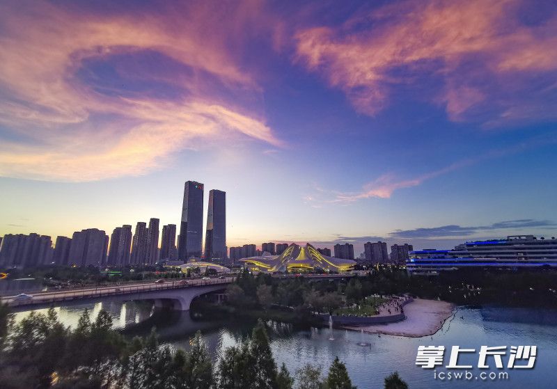 梅溪湖畔绿岛的沙滩上，众多市民一边休闲纳凉、一边欣赏晚霞美景。