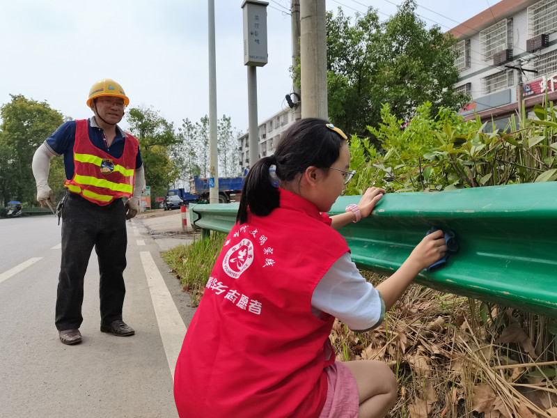 宁乡市志愿者在清洁道路围栏。