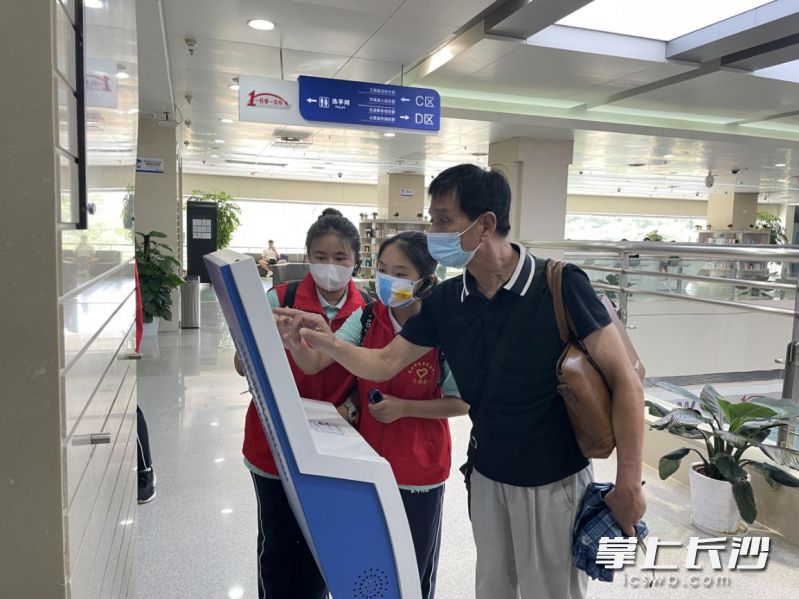 在长沙市政务服务大厅，学生志愿者帮助办事群众取号。 均为长沙晚报通讯员 汪泽国 供图
