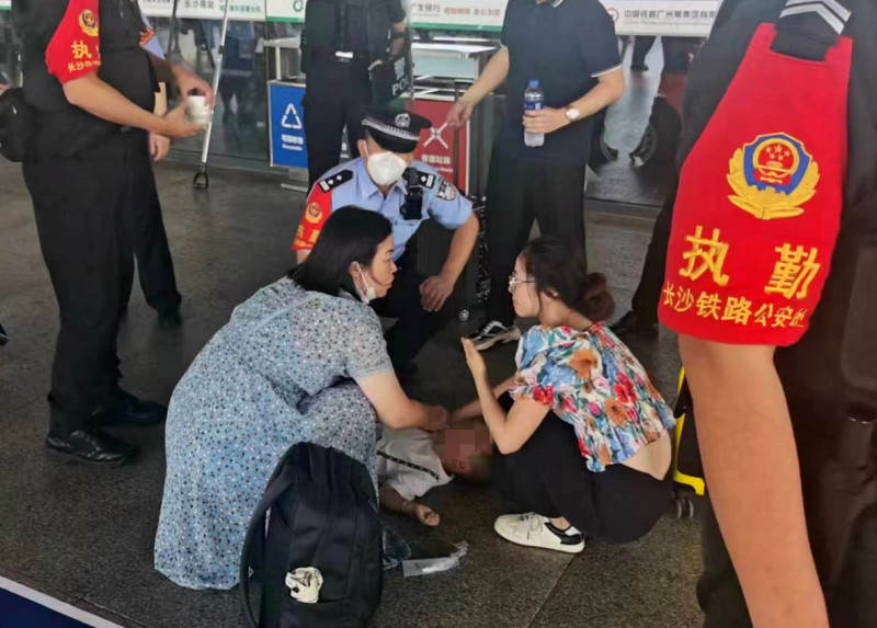 男孩倒地抽搐，热心旅客（左）和民警等人参与救助。 均为长沙晚报通讯员 张威 供图