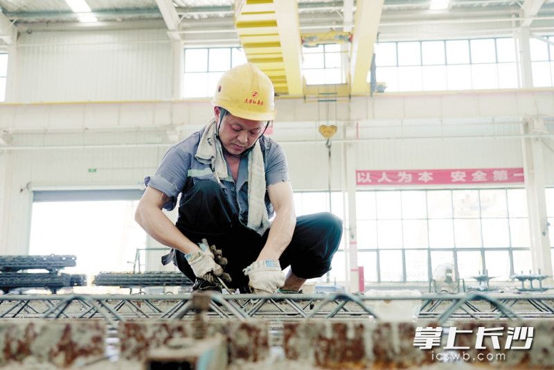 俯身绑扎钢筋，工人师傅汗流浃背。长沙晚报通讯员 朱莉 摄