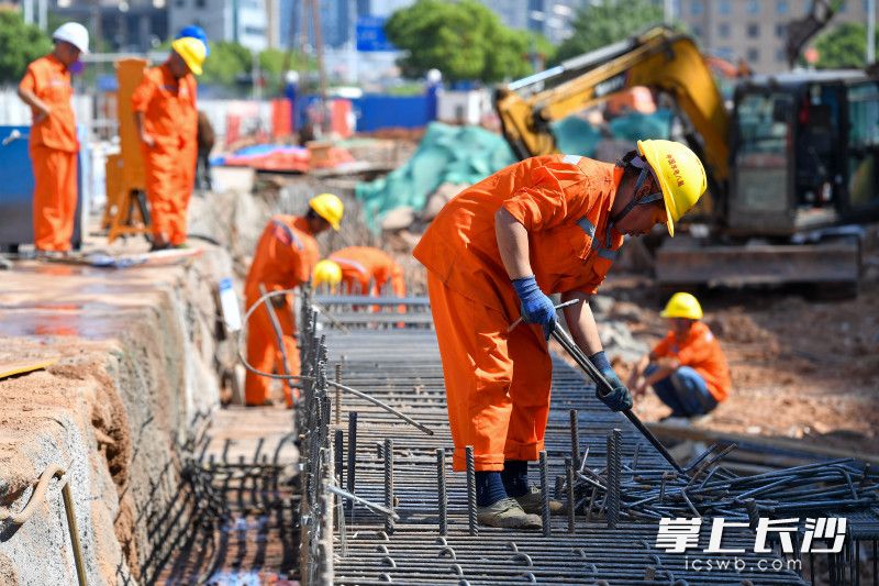 60多名工人头顶烈日，正在进行冠梁浇筑和表层土清理施工，为即将到来的车站主体施工做准备。