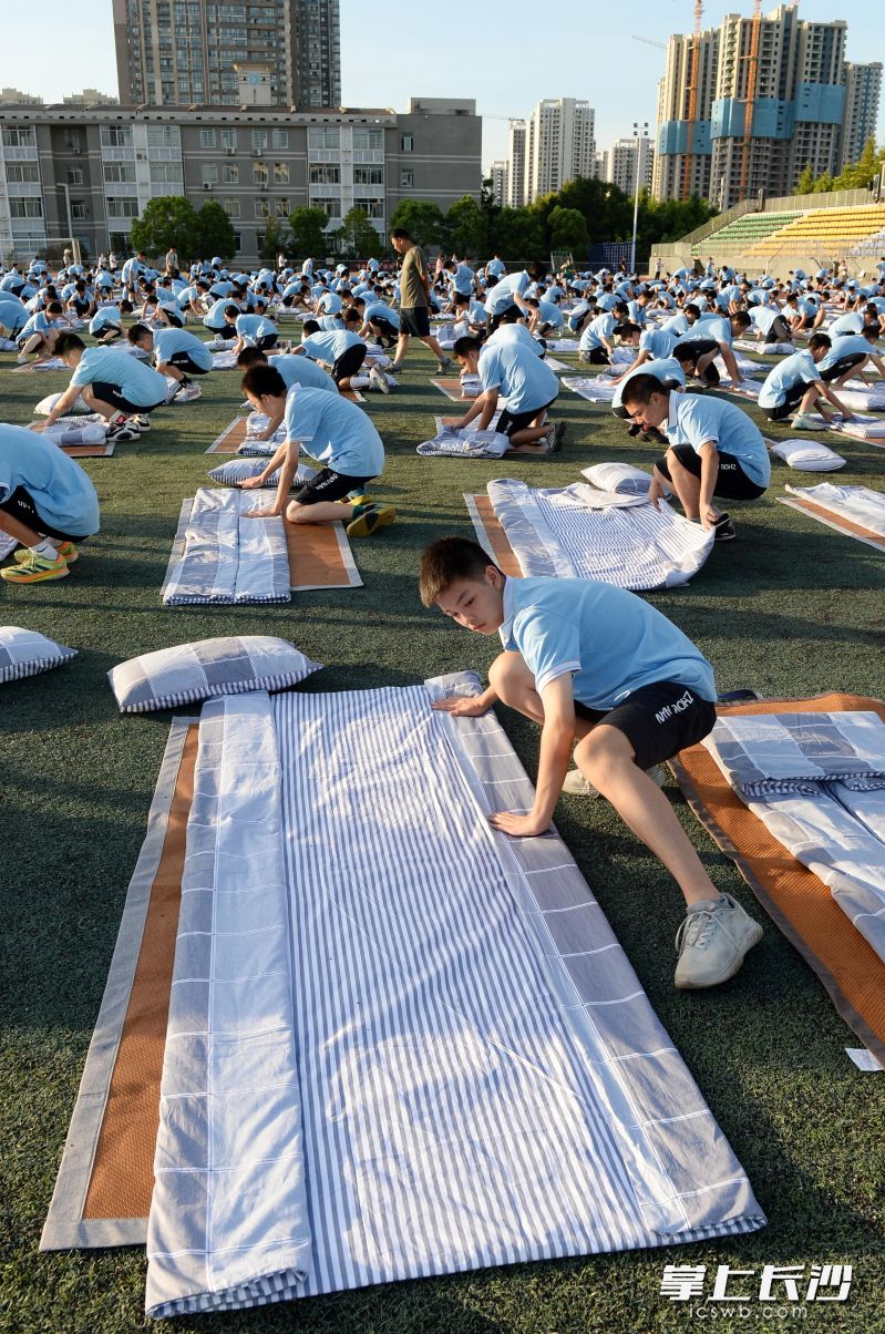 以地为席，周南中学高一学子在操场开展叠被子比赛。均为长沙晚报全媒体记者石祯专、实习生张芊晔摄