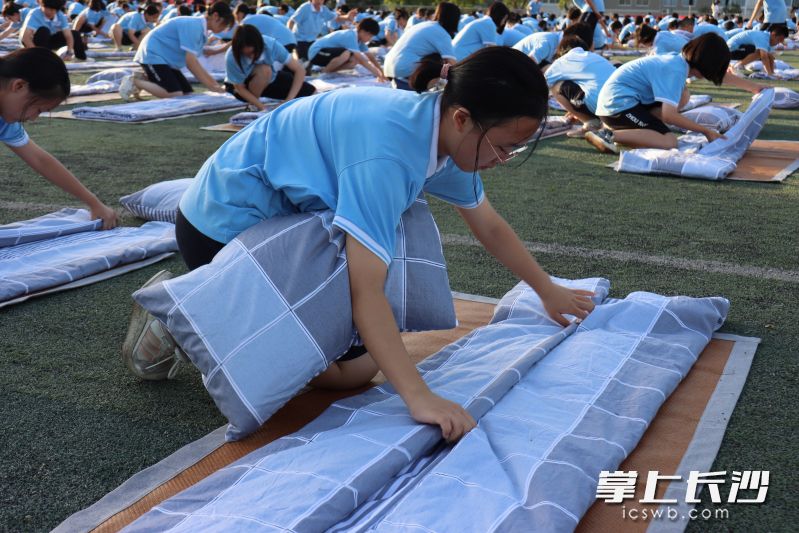 一名学子正在精心叠被子。