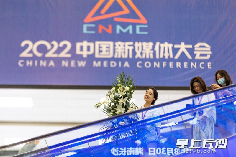 2022中国新媒体大会LOGO前，一名女士微笑经过。长沙晚报全媒体记者 董阳 摄