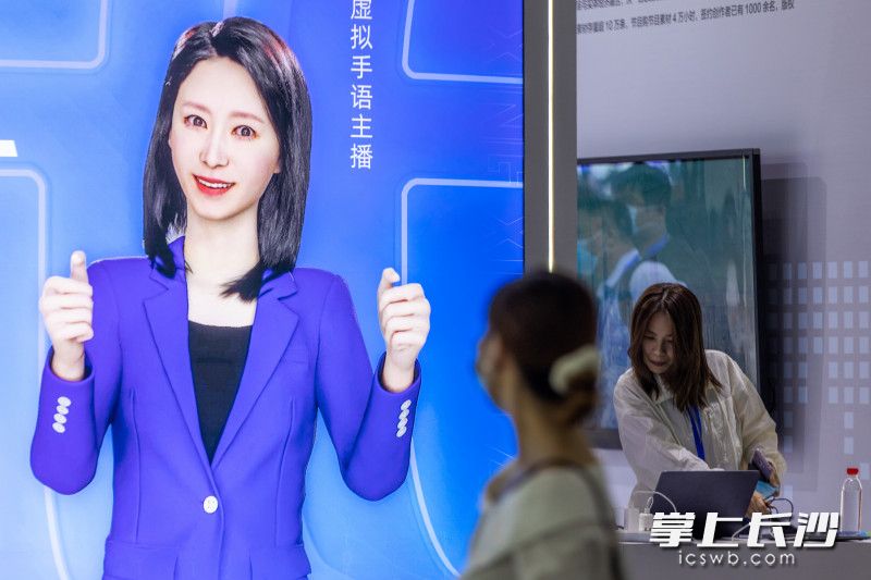 2022中国新媒体大会LOGO前，一名女士从虚拟手语主播展牌前经过。长沙晚报全媒体记者 董阳 摄