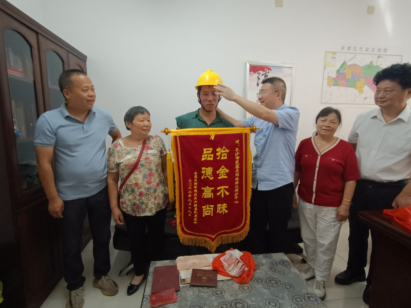 李文广十分腼腆地接过周爱玲（左二）送来的锦旗。均为长沙晚报实习生 曾惠玲 摄