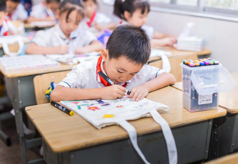 低年级同学在空白帆布包上自由创作法治主题作品。
