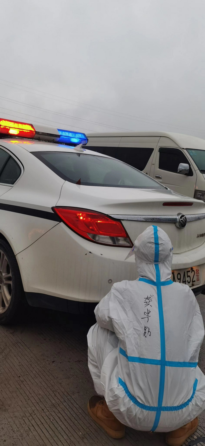 长沙西高速出入口，警车亮灯引导车辆通行，防疫人员忍不住就着排气管暖手。通讯员 肖强 摄