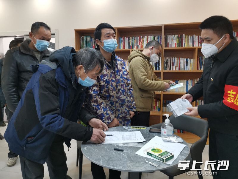 在“长沙快递货车司机红色之家”开福区传化物流港站，货车司机们排队领取抗疫药品和口罩。