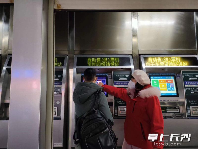 高慧明正在帮助乘客取票。