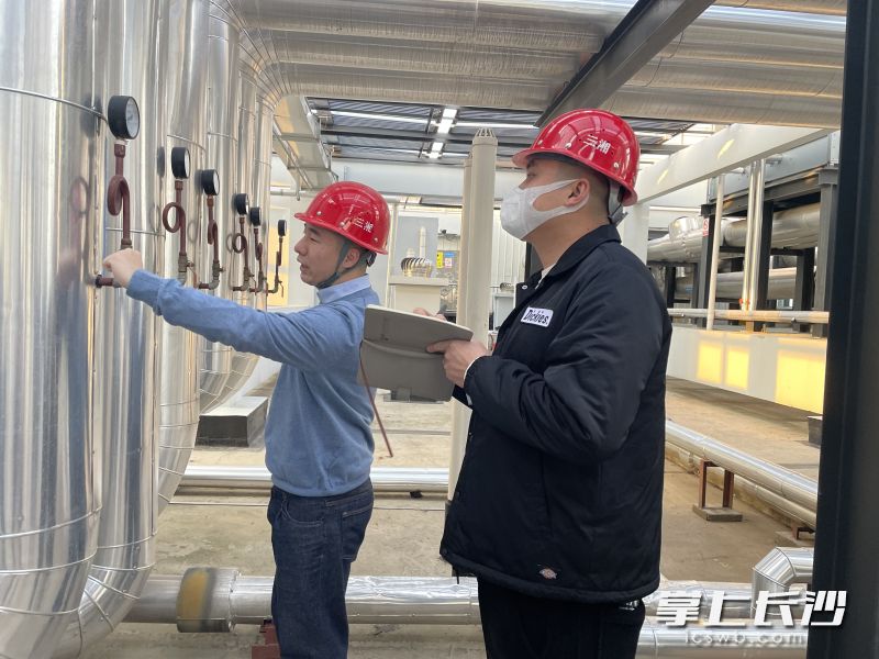 史伟奇和同事正在大楼顶层仔细检查空调机房压力泵、空调冷却塔。长沙晚报全媒体记者 颜家文 摄