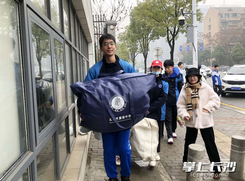 高一新疆班的学生志愿者帮助同学搬运行李。  均为长沙晚报全媒体记者石祯专，通讯员宋婧、李雨晴、蔡远翔摄
