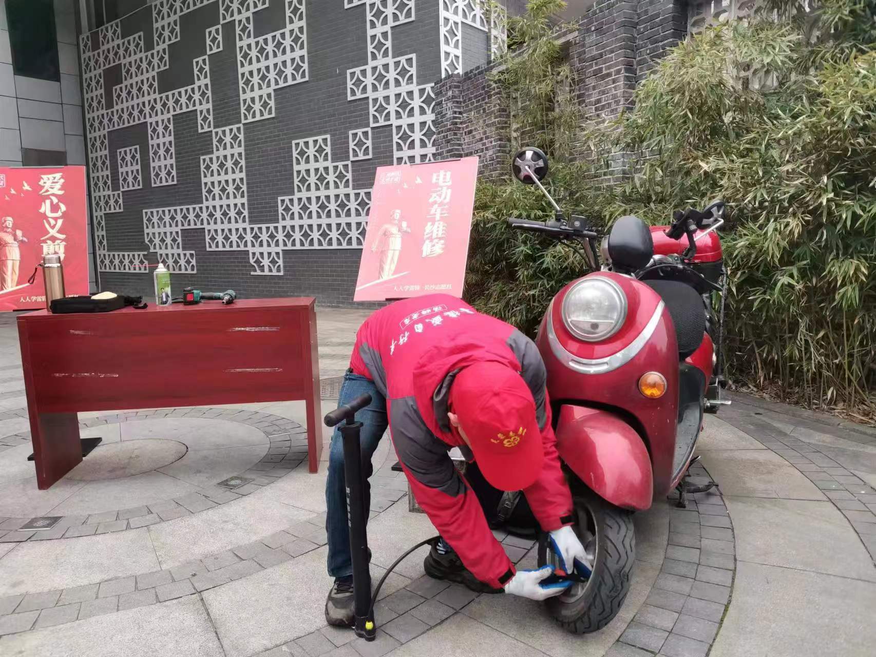 志愿者正在认真为居民修理电动车。