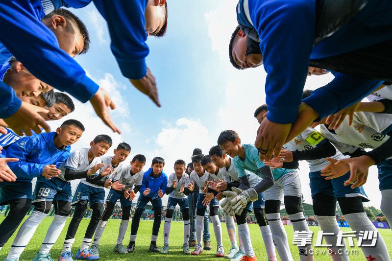 比赛前，长沙德馨园小学足球队队员和教练员围成一圈，一起加油鼓劲。  均为长沙晚报全媒体记者郭雨滴摄