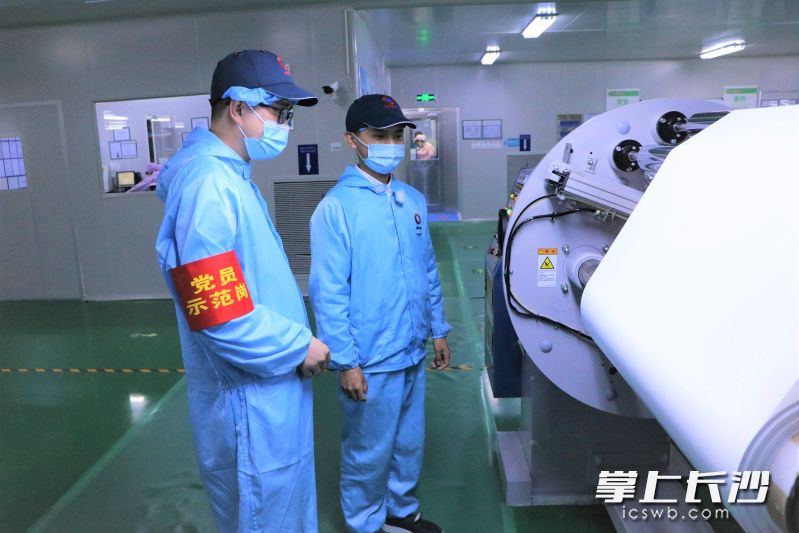 在中材锂膜涂覆工厂里，负责人王连杰（左）正在查看涂覆膜收卷情况。长沙晚报全媒体记者 张禹 通讯员 赵璞 摄