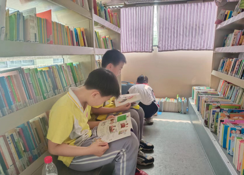 几名学生在图书巴士上选书、看书。长沙晚报全媒体记者 陈良 摄