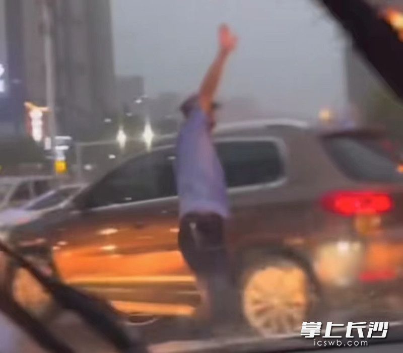市民谭先生拍下的雨中一幕，辅警刘康在雨中疏导交通。视频截图