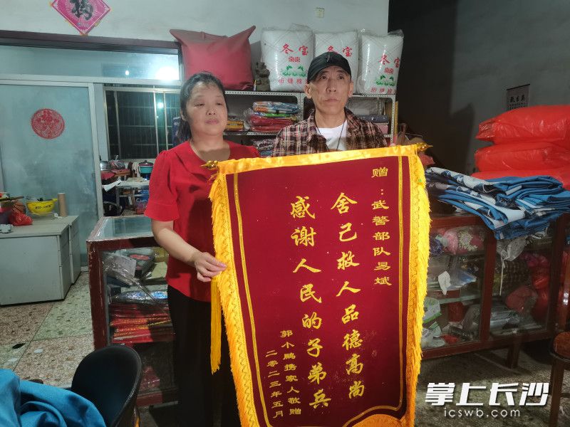 郭先生将一面锦旗送给易斌的母亲，表达谢意。受访者供图
