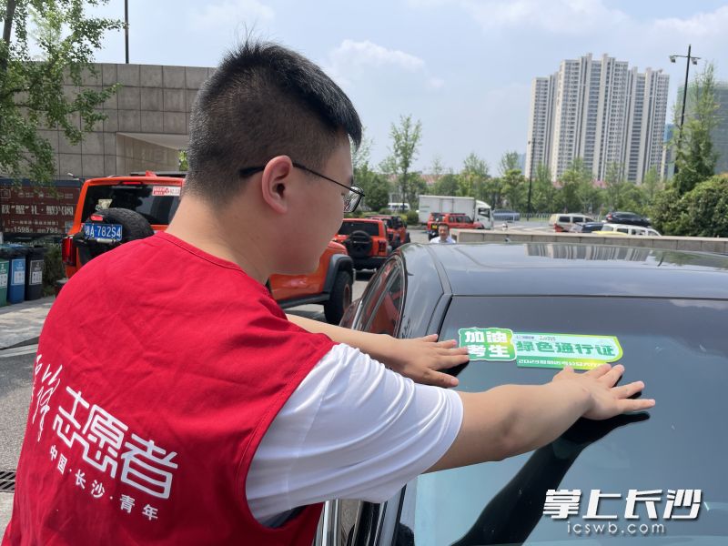 雷锋志愿者将通行证贴在车上，将为高考考生提供免费送考服务。
