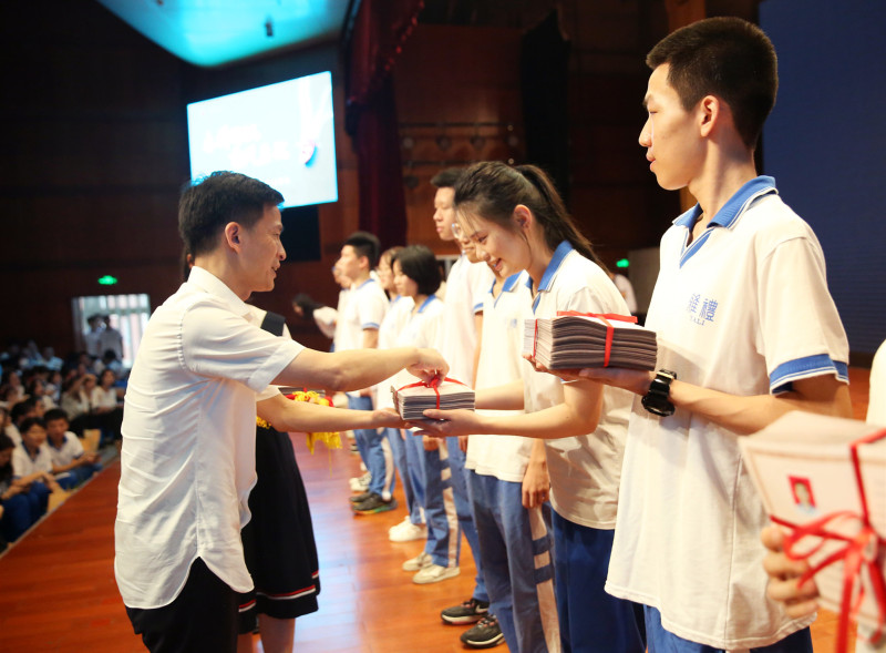给学生代表颁发毕业证。