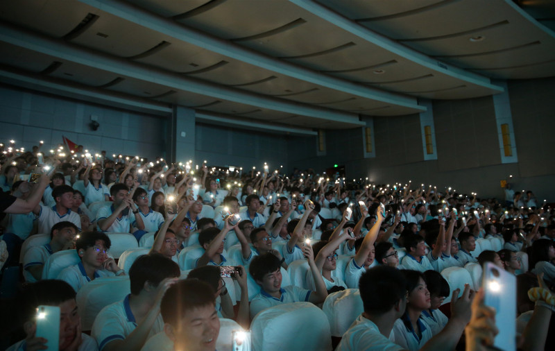 台下同学们打开手机上的电筒，与台上表演的师生互动。