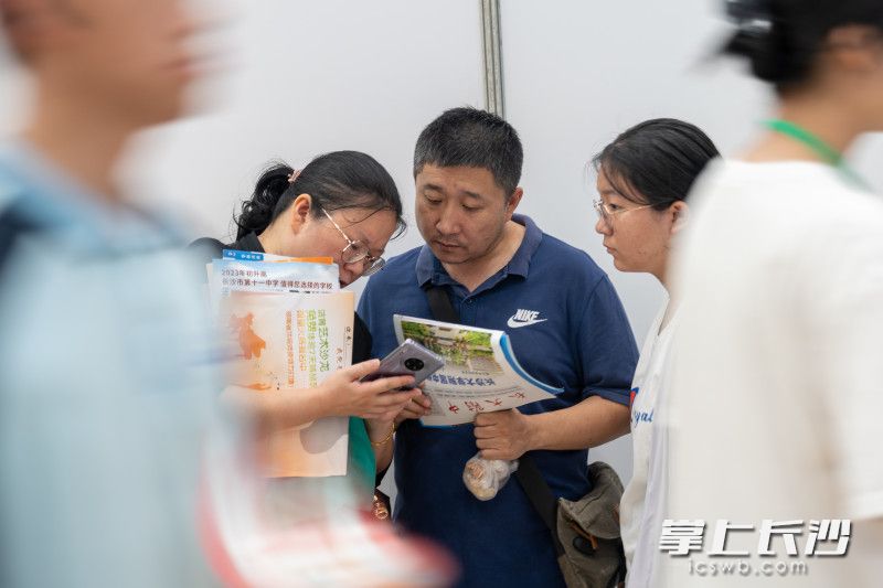 活动现场，一家三口正用手机查询报考学校的招生信息。