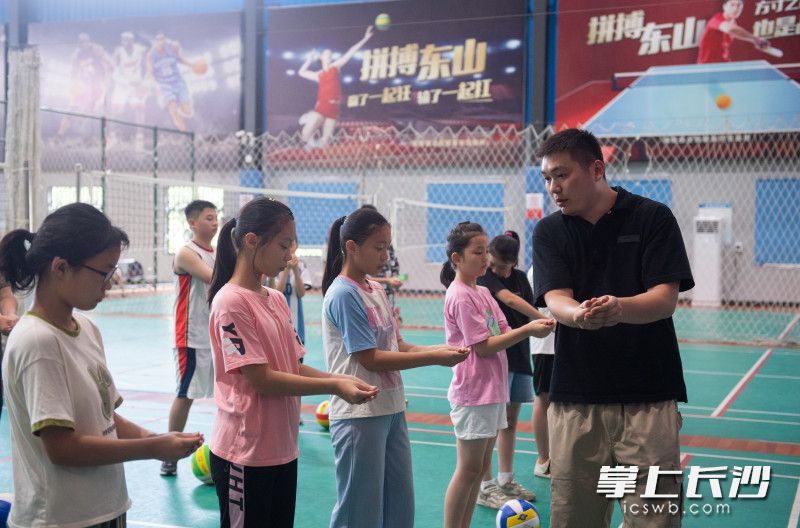 东山全民健身中心排球教练正在给学生们讲解排球颠球的动作要领。