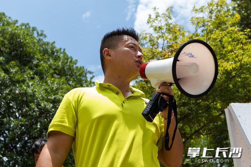 36℃高温下，甘晓恬拿着扩音器喊话，引导部分游客到新乘车点排队候车。