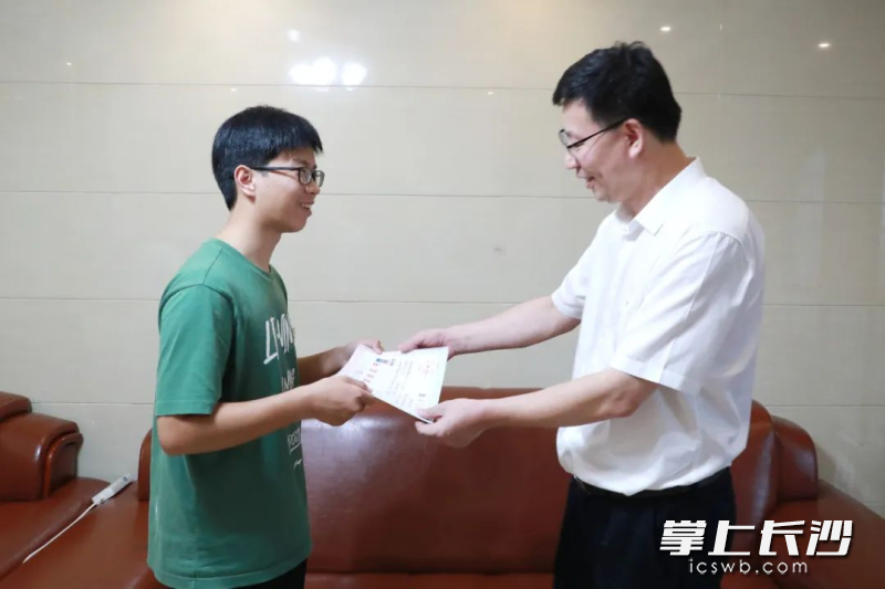 中国工程院院士、中南林业科技大学校长吴义强为新生张凯送上录取通知书。