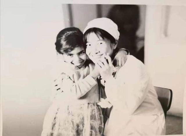 张友明身穿白大褂，搂着一个大眼睛的阿尔及利亚小姑娘。  均为医院供图