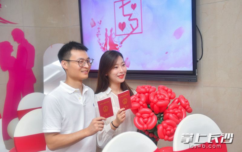 一对新人拿着结婚证拍照，记录美好时光。均为长沙晚报全媒体记者 邹麟 摄