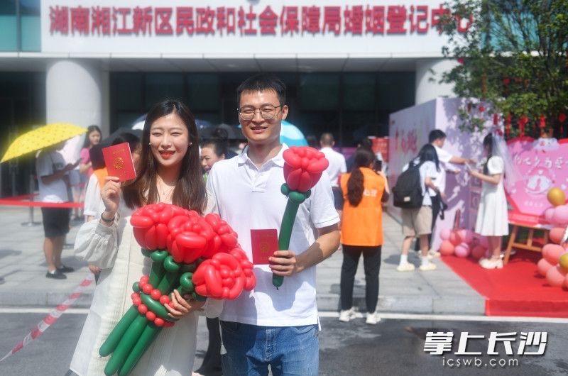 刚拿到证的一对新人在湘江新区婚姻登记处门口拍照记录。