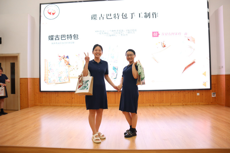 两位老师化身模特，展示自制的手提帆布包。