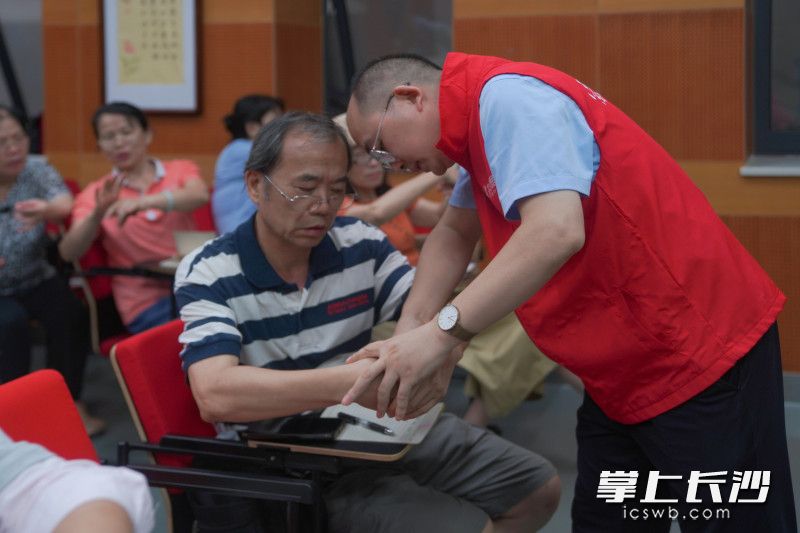 中医养生保健课上，志愿老师手把手指导学员。