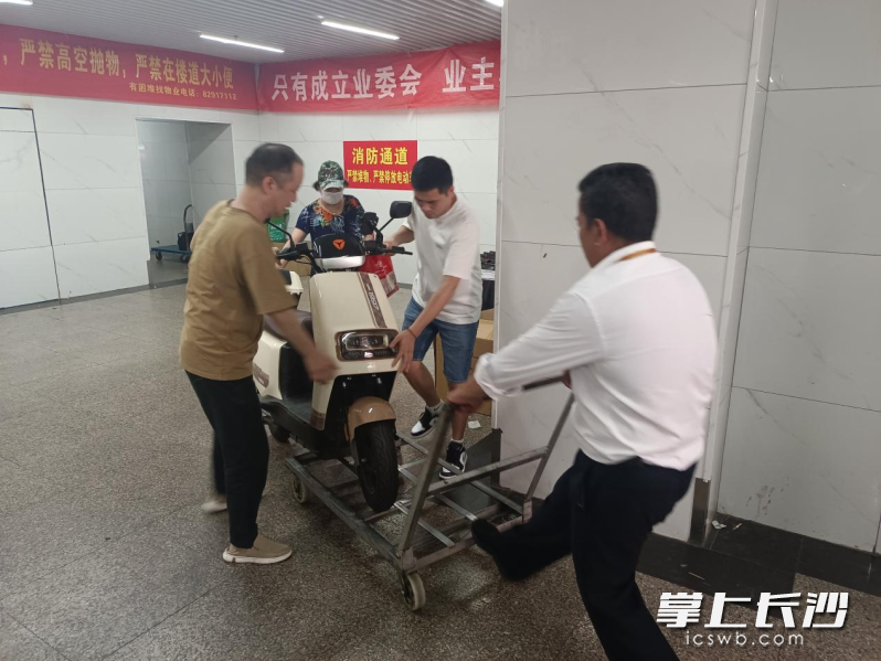 大楼物业公司工作人员也来到现场，将违规停放的电动车移出大厅。