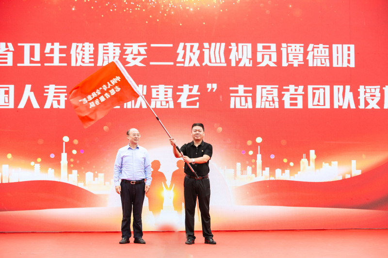 省卫生健康委二级巡视员谭德明为“金秋惠老”志愿者服务队代表授旗。