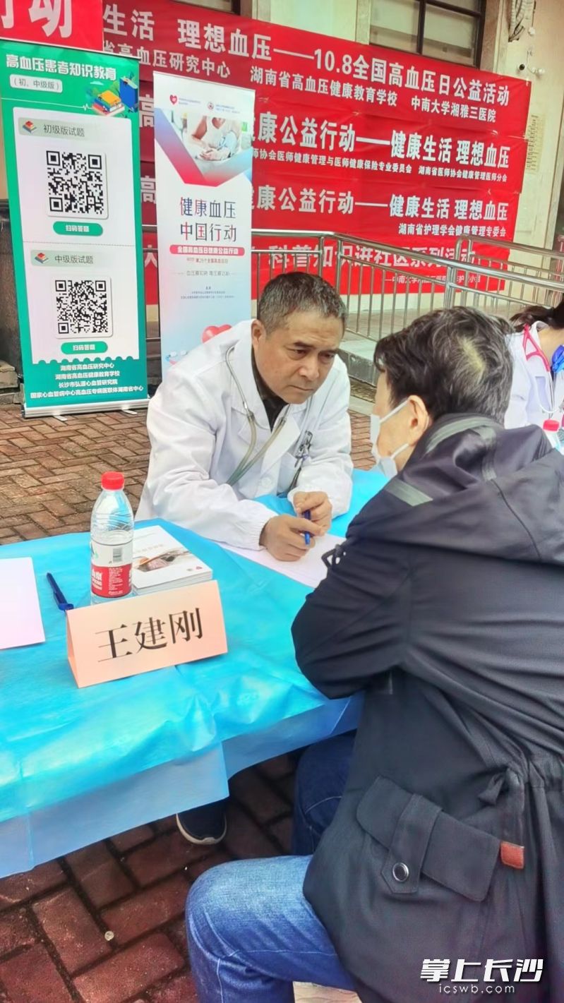 健康管理专家在认真听取群众咨询高血压疾病相关问题。