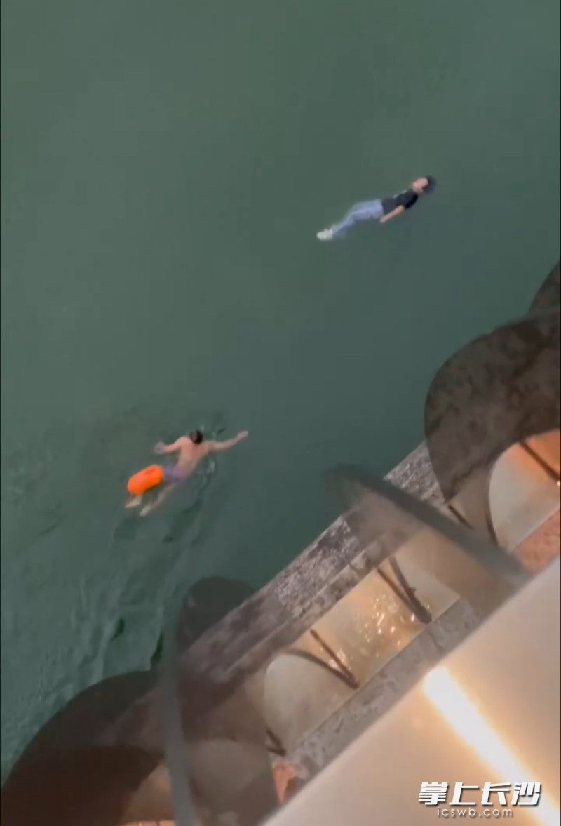 成维身上绑着救生浮球，快速游向溺水男子。视频截图