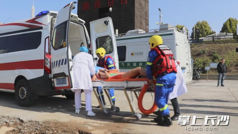 医护人员和救援队员将落水伤员抬至救护车上。