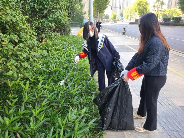 两名志愿者在捡拾路边绿化带中的垃圾。长沙晚报通讯员 陈眺 杨凯 供图