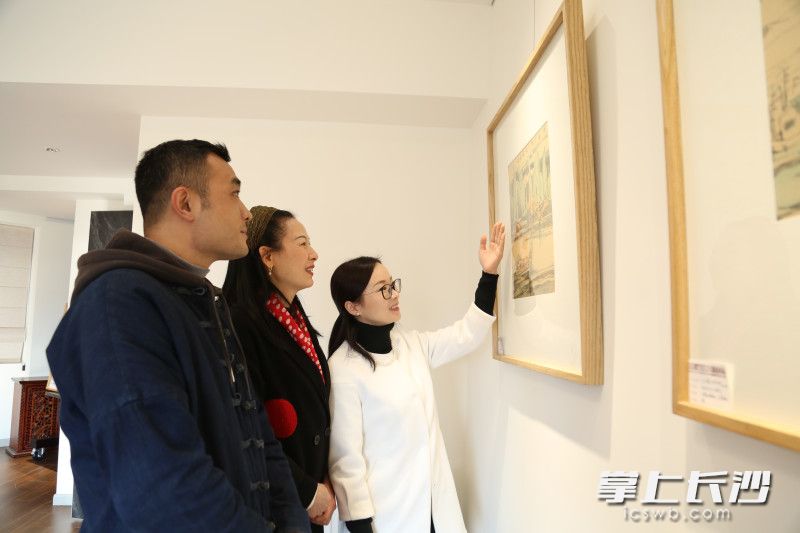 黄定初弟子紫文向来客介绍老师的画作。