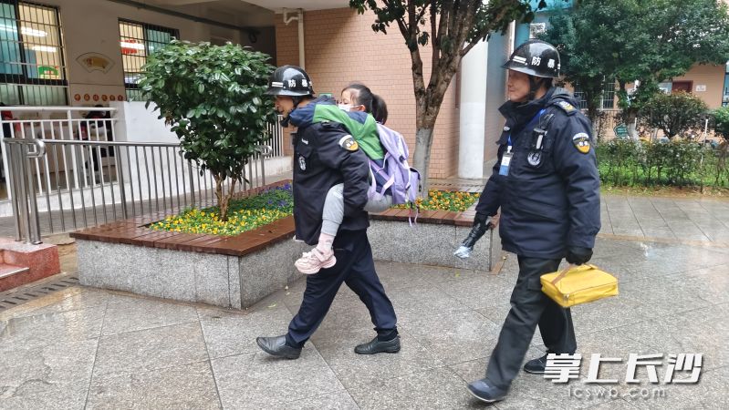 保安曹智和刘江轮流背着小女孩去教室。  均为长沙晚报通讯员王国光摄