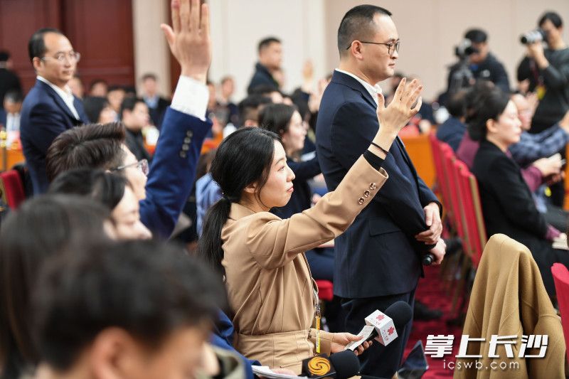 记者们在举手提问。