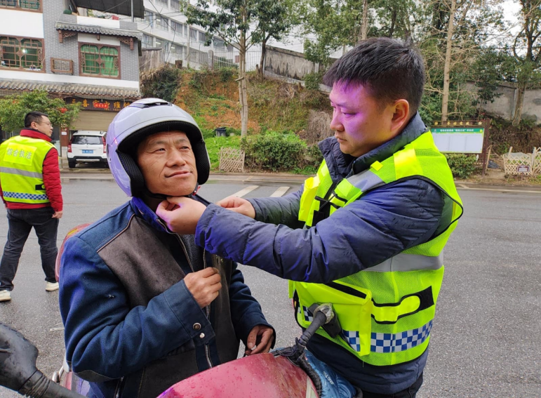 工作人员教村民如何正确佩戴头盔