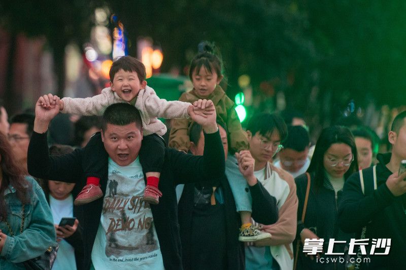 一位家长背着小孩在长沙街头快乐“飞翔”。