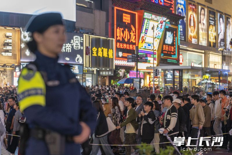 “五一”假期第二天，长沙游人如织，五一商圈游客身旁，警车警灯闪烁，民警值勤守护。均为长沙晚报全媒体记者 周数邑 摄